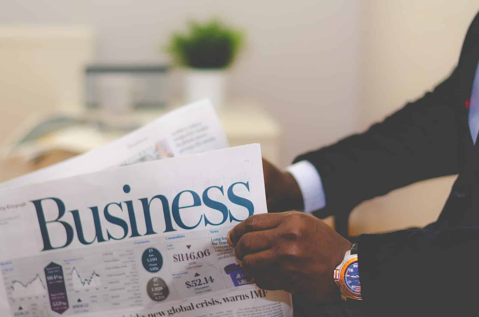 person wearing suit reading business newspaper